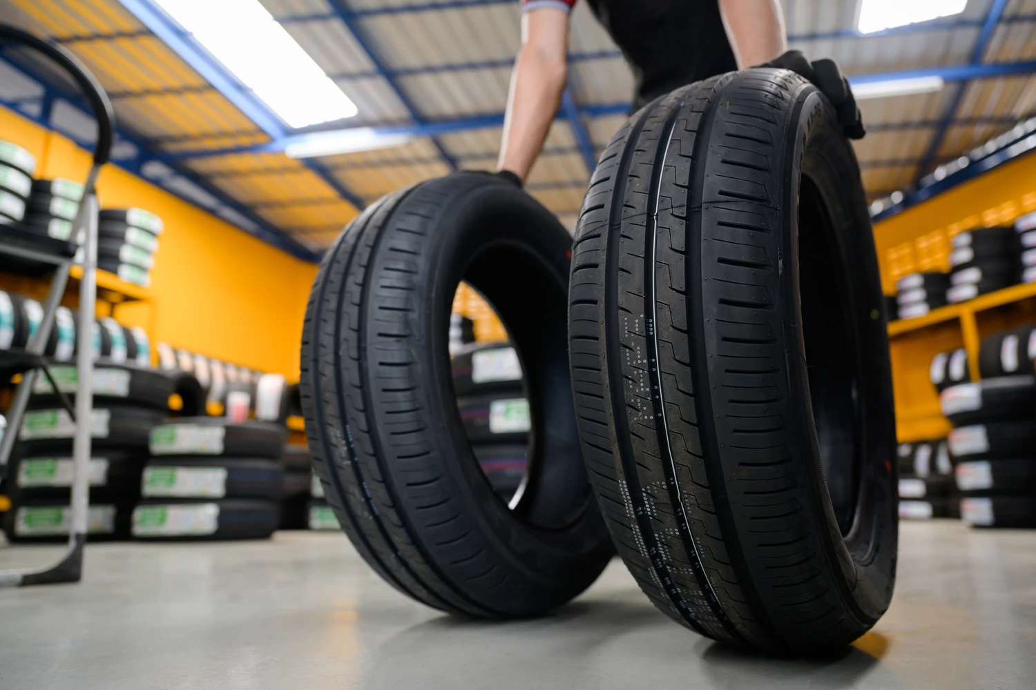 In a bustling tire shop, a worker skillfully balances two high-performance tires